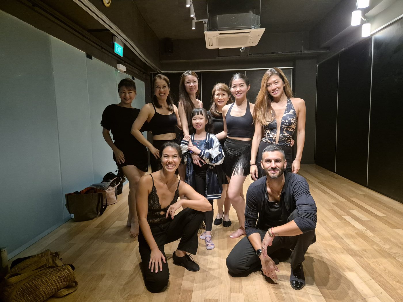 A group of adult students and Raliza posing in a dance studio after class