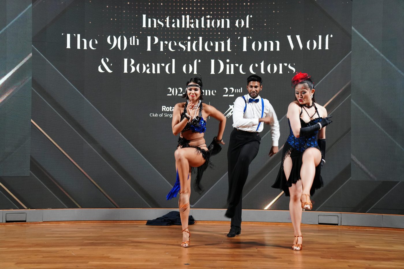 Raliza and two dancers performing a Latin show on stage at a Rotary Club installation dinner