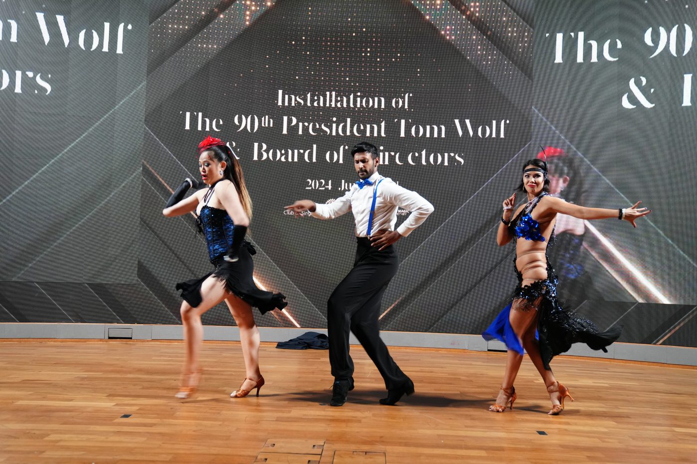 Raliza and two dancers performing a Latin show on stage at a Rotary Club installation dinner