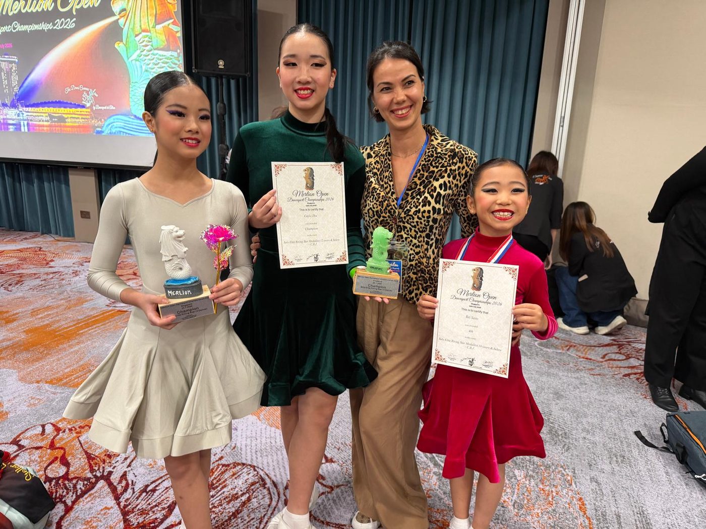 Raliza with three young students holding trophies and certificates at a competition