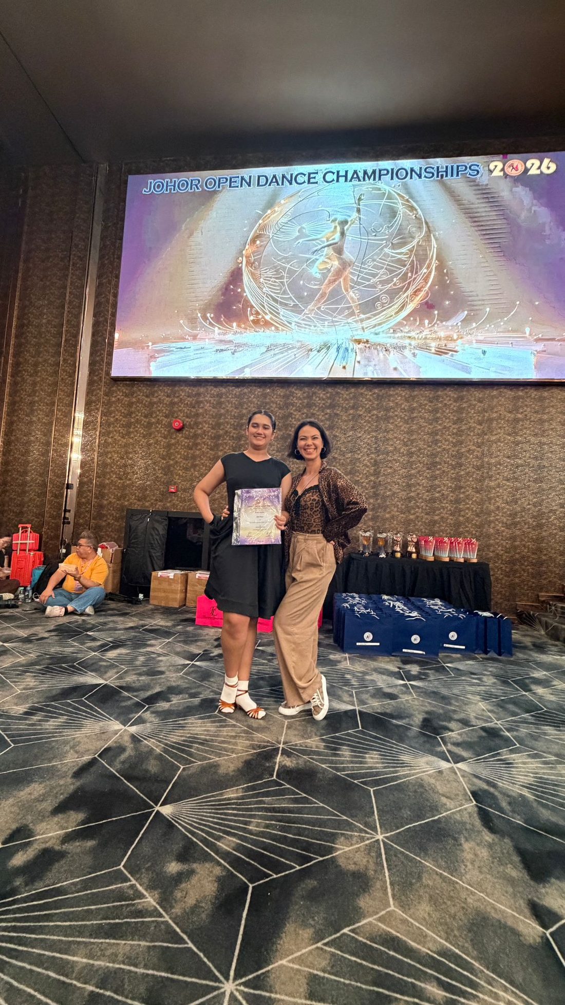 Raliza with a female adult student holding her certificate at the Johor Open Dance Championships