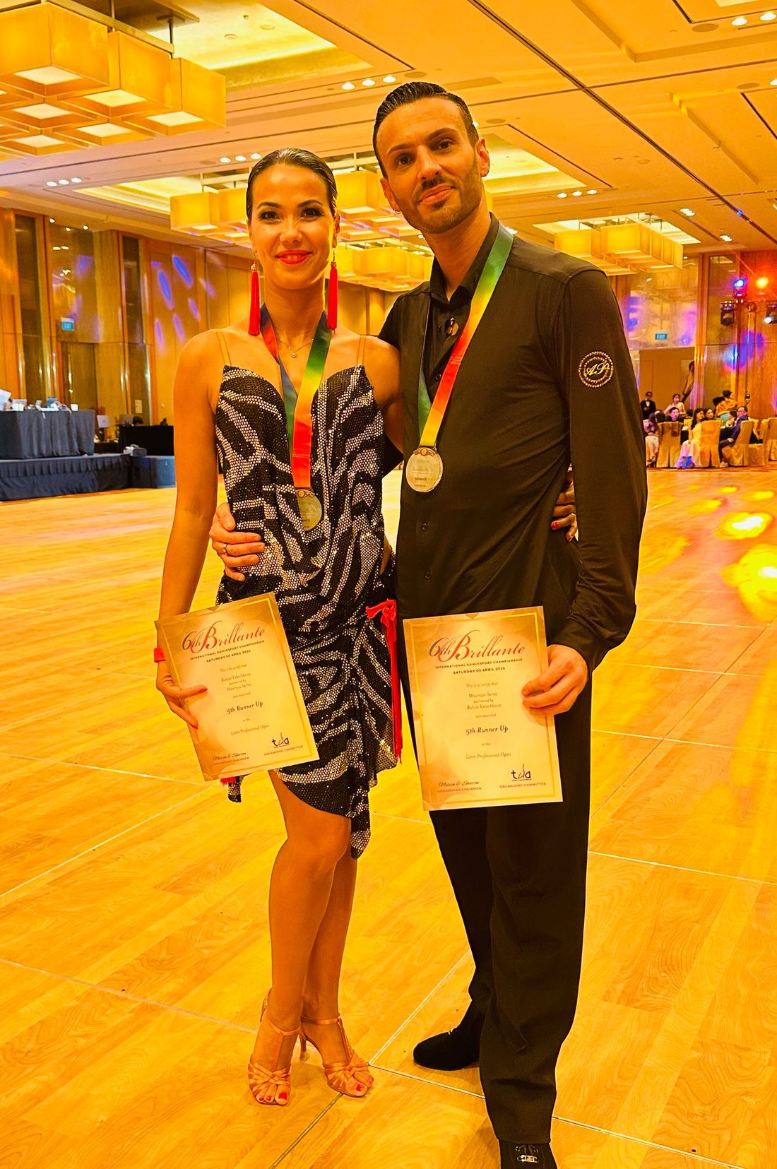 Raliza and an adult student with medals and certificates after a competition