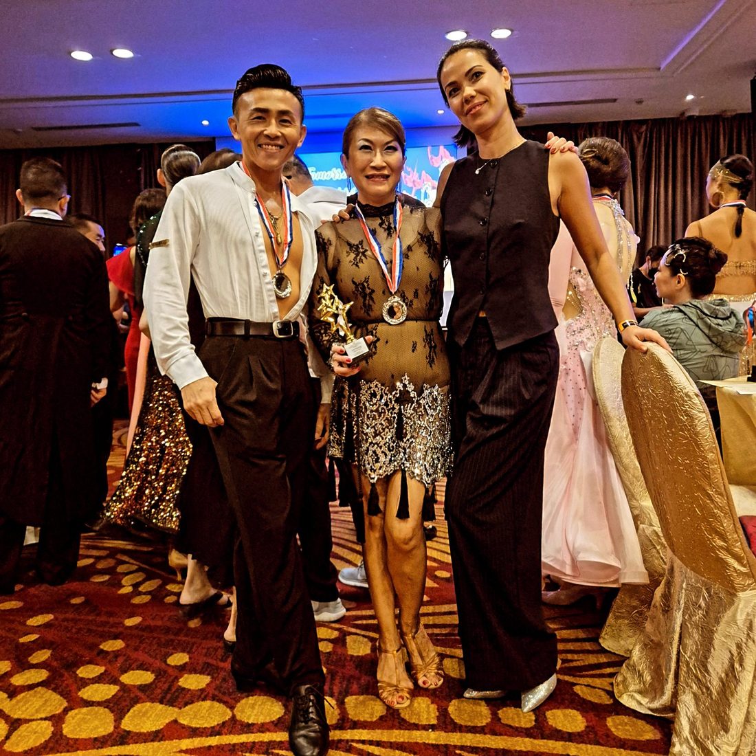 Raliza smiling with an adult student who is holding a trophy after a competition